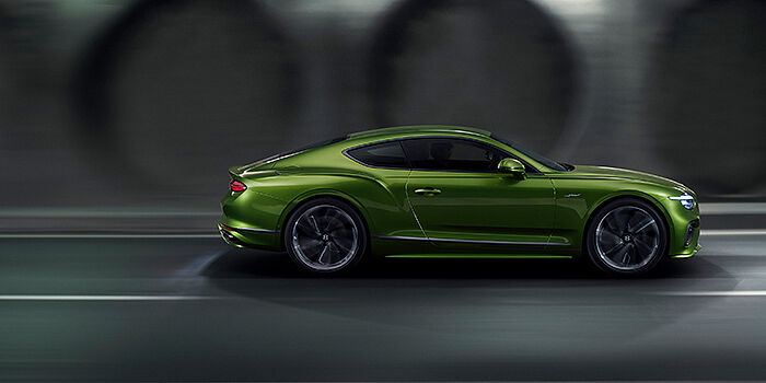  Bentley Douglas Bentley Continental GT coupe in Tourmaline Green paint driving in profile on a dark road